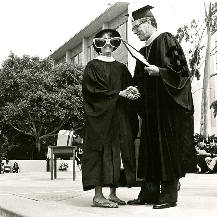graduating student shaking hands and wearing oversized sunglasses
